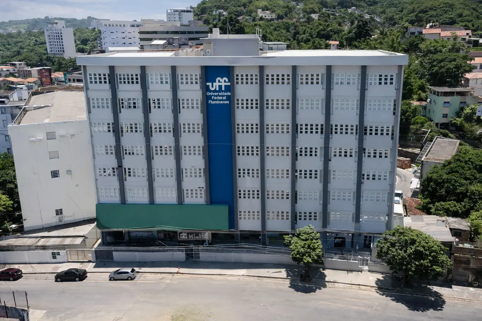 Prédio da UFF em Niterói visto de cima, com fachada branca e azul, entorno urbano e morros ao fundo, em cena usada para contextualizar a presença da universidade na cidade.