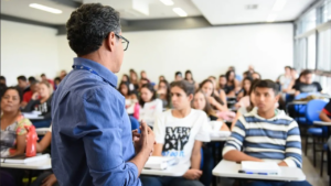 Professor orienta estudantes em sala de aula sobre como consultar cursos reconhecidos pelo Ministério da Educação.